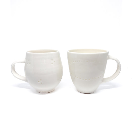 Two white ceramic mugs with a textured pattern