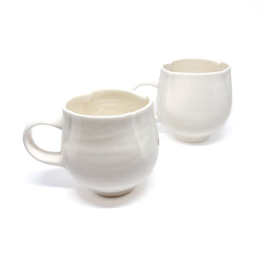 Two white ceramic mugs, one with a textured surface and the other smooth.