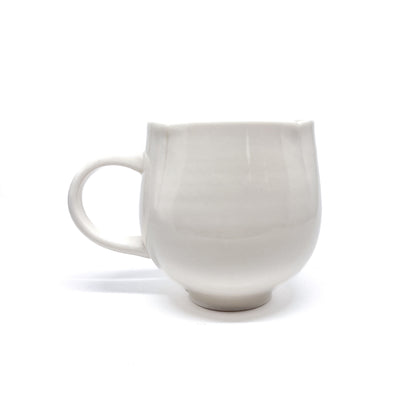 A white ceramic mug with a handle and a slightly flared rim.