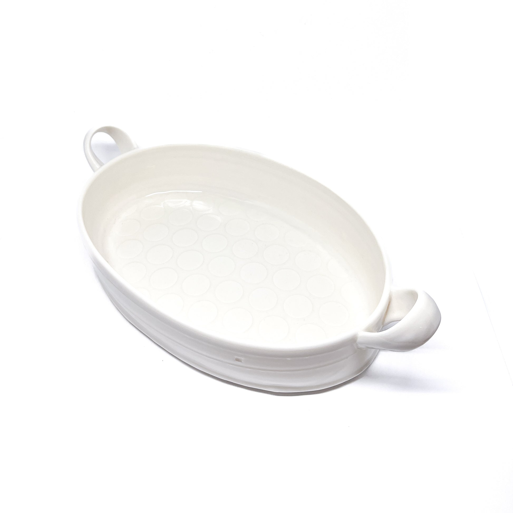 A white oval ceramic casserole dish with handles on each side.
