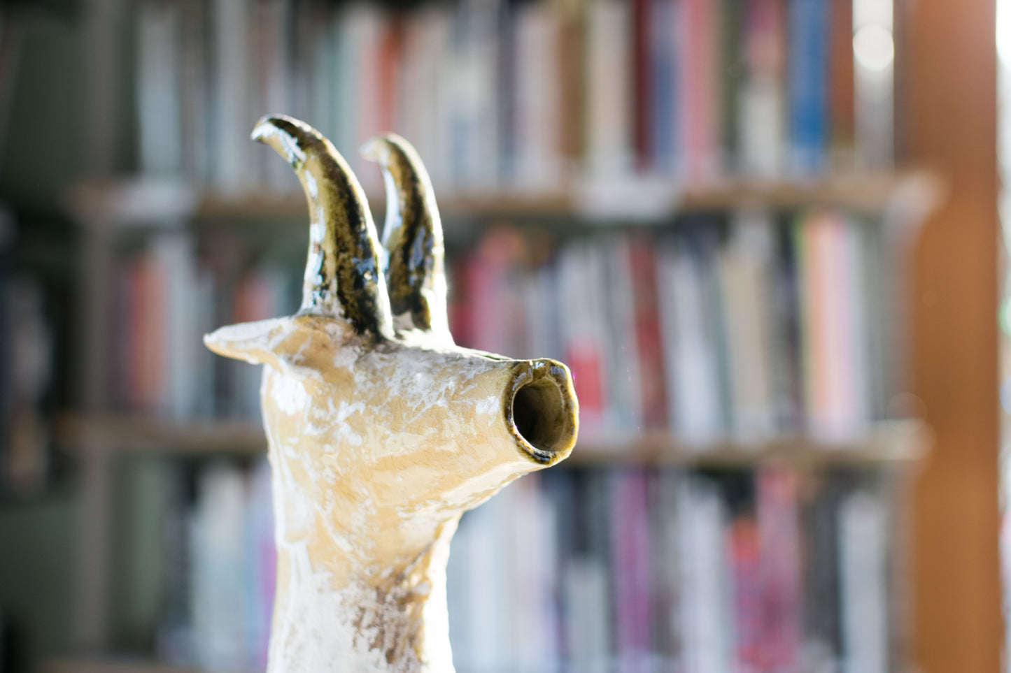 Close-up of a textured ceramic Long Neck Bull head with tall, curved horns and a distressed light-toned glaze with white accents.