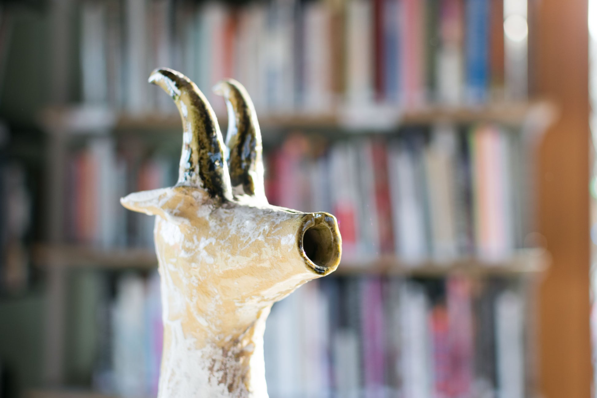 Close-up of a textured ceramic Long Neck Bull head with tall, curved horns and a distressed light-toned glaze with white accents.