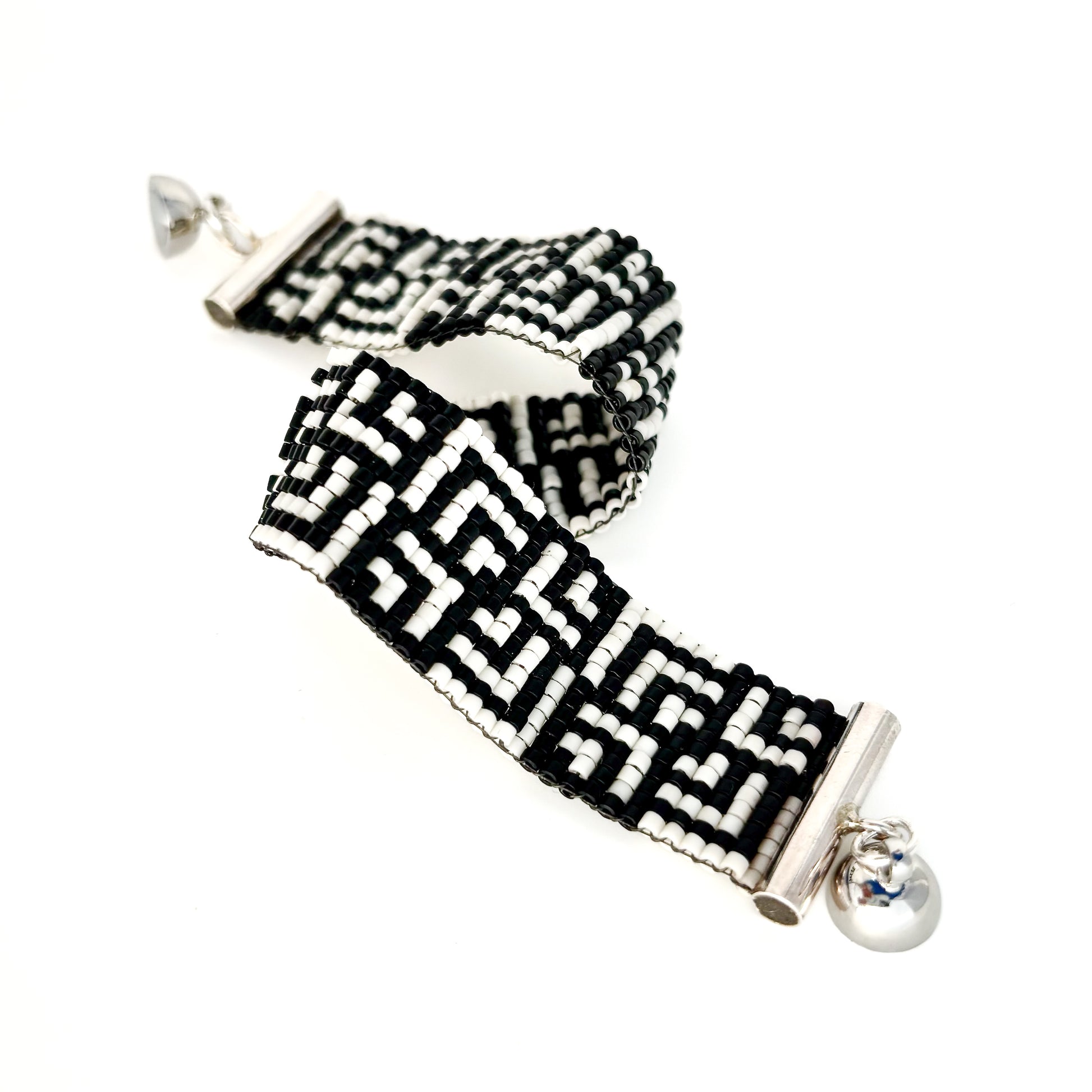 Two beaded bracelets with black and white Greek key patterns feature silver magnetic ball clasps.