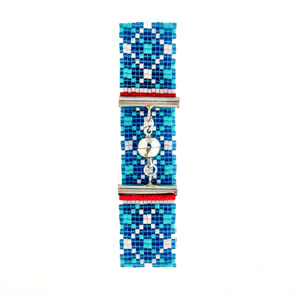 A flat lay shows a beaded bracelet with a blue, light blue, and white geometric pattern and a silver magnetic clasp.
