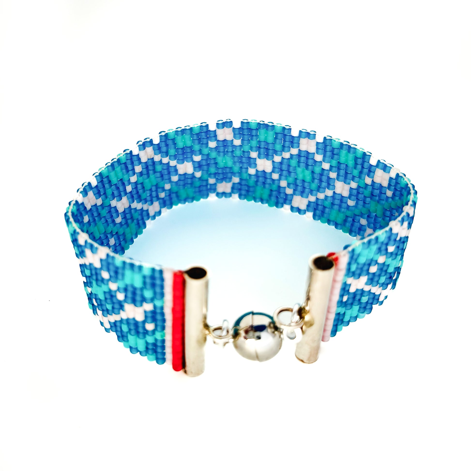A beaded bracelet with a blue, light blue, and white geometric pattern has a silver magnetic clasp.