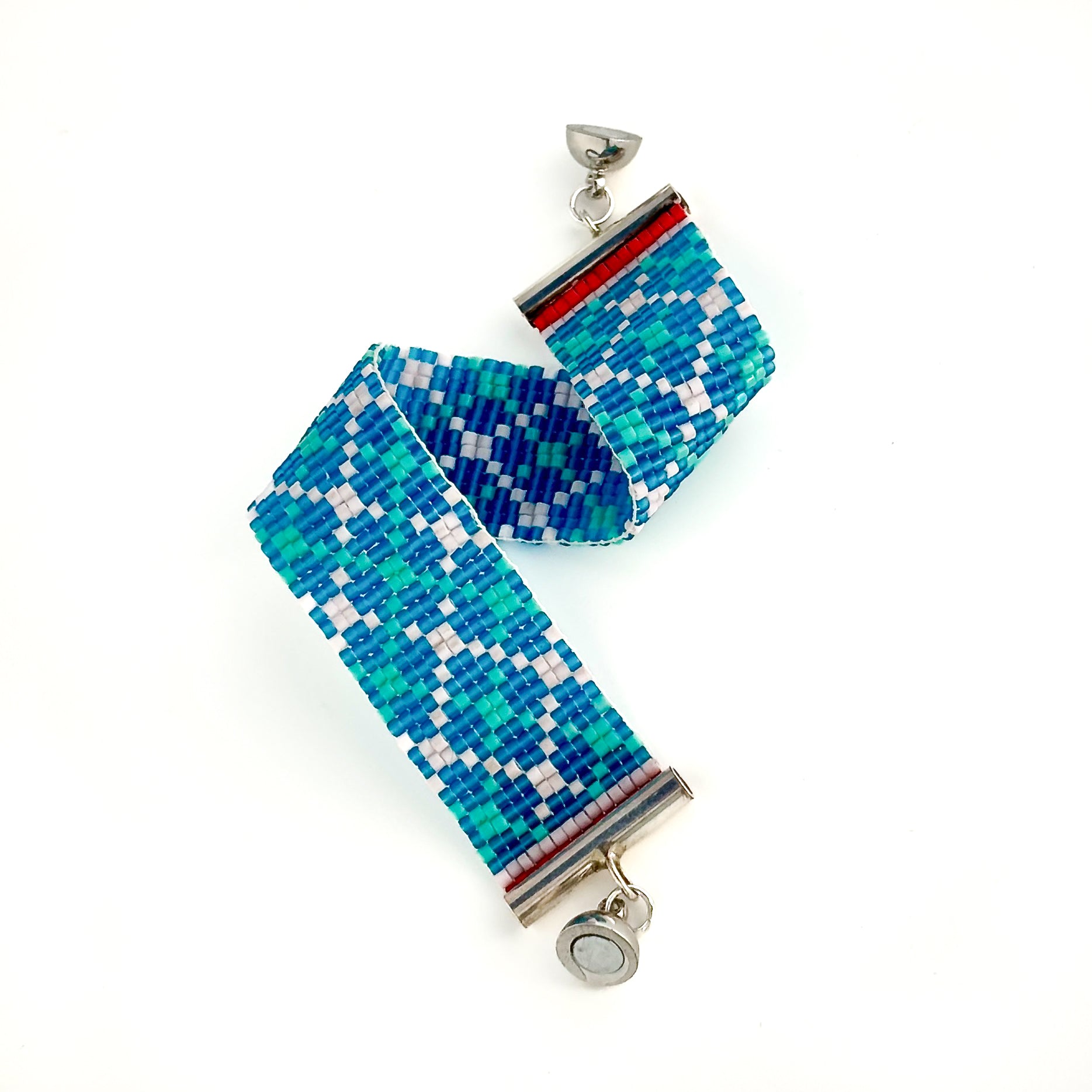 A beaded bracelet with a blue, light blue, and white geometric design has a silver magnetic ball clasp.