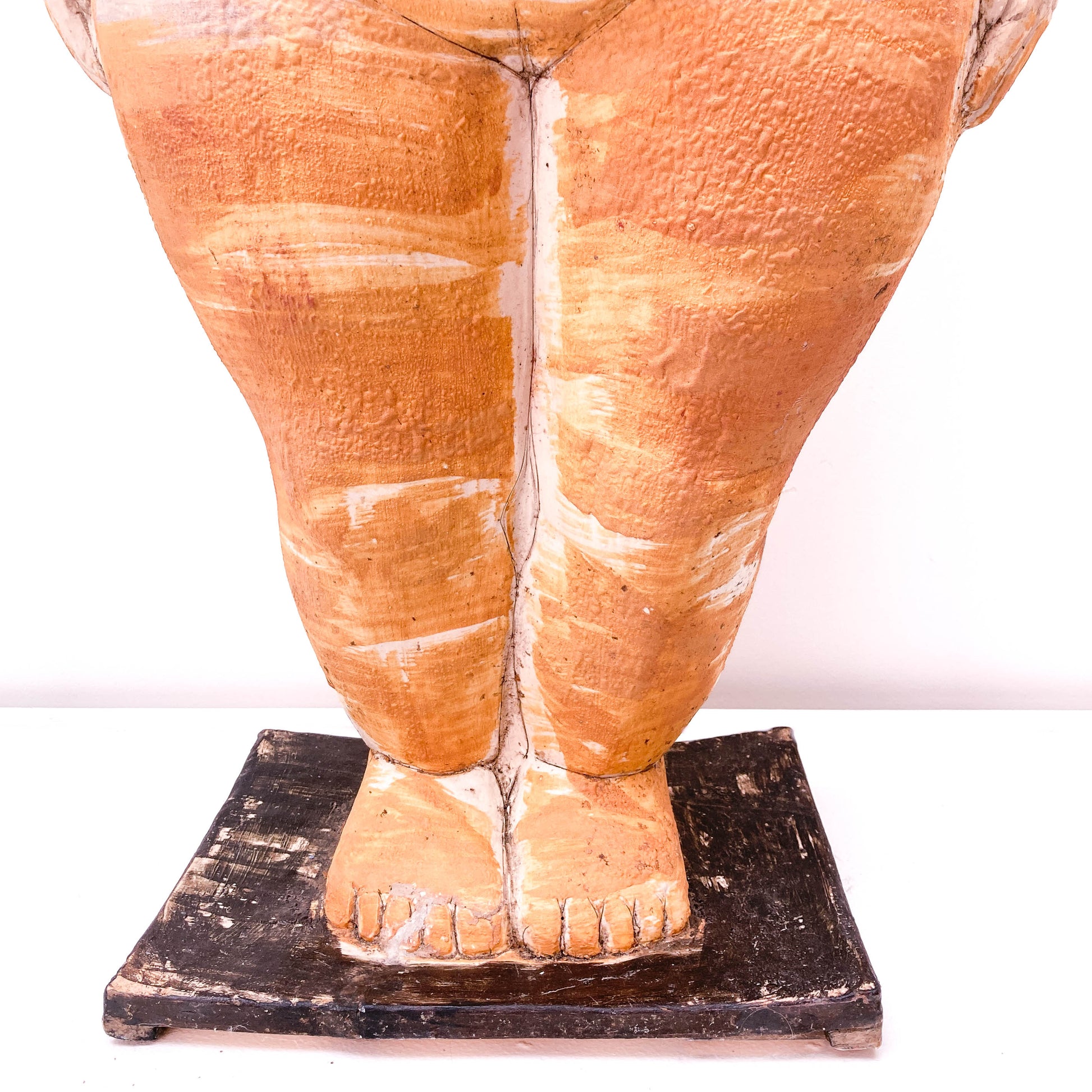 A close-up of a baby sculpture legs and feet on a black base.