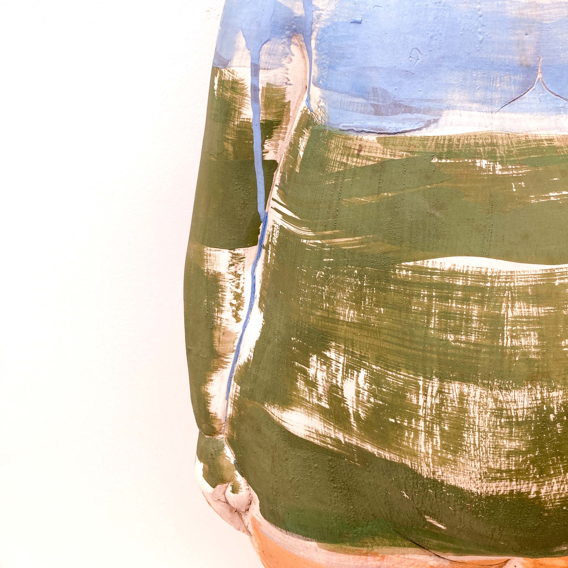 A close-up of a baby sculpture torso with blue and green paint strokes.