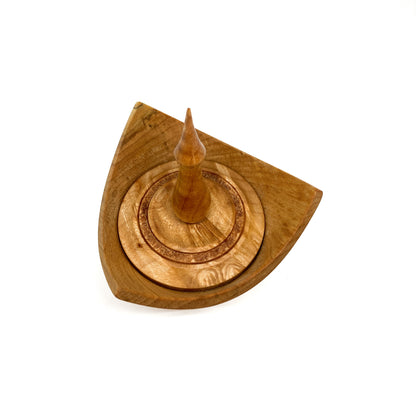 A turned wooden box with a pointed finial on the lid, viewed from above.
