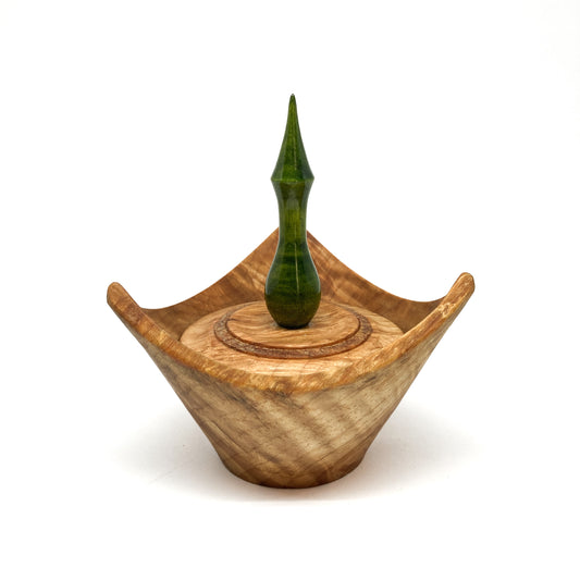 A turned wooden box with a pointed green finial on the lid.
