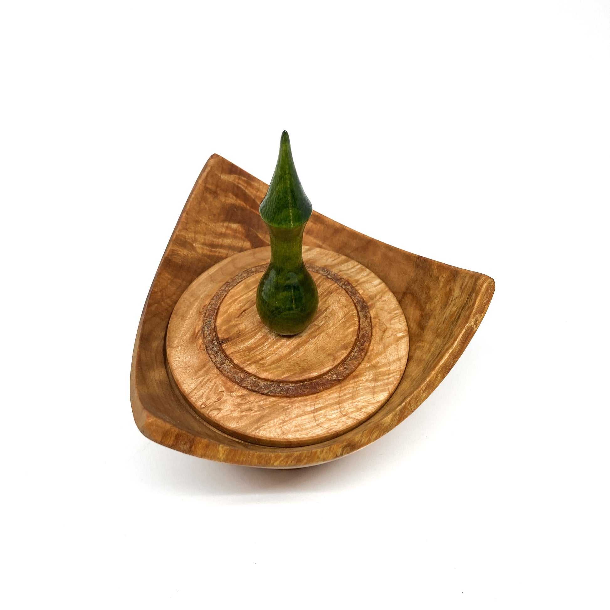 A turned wooden box with a pointed green finial on the lid, viewed from above.