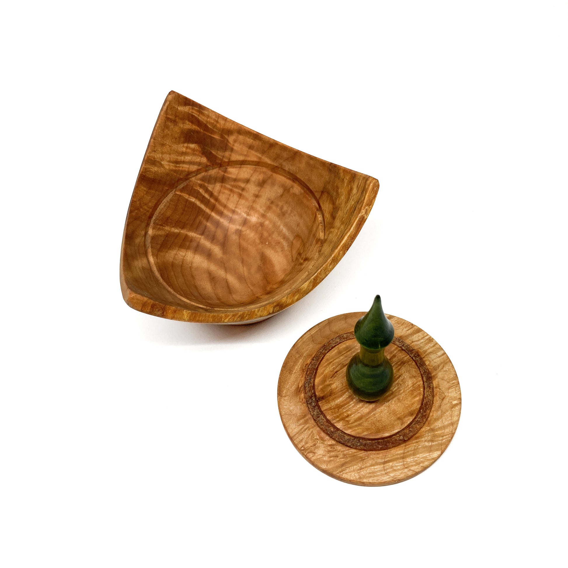 A turned wooden box with a pointed green finial on the lid, with the lid removed.