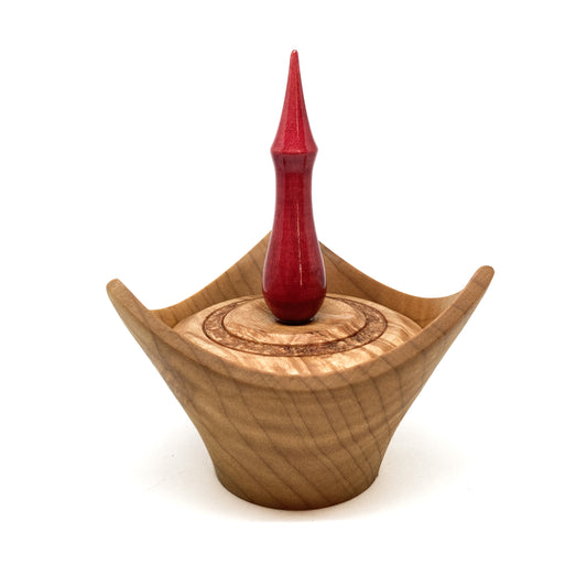 A turned wooden box with a pointed red finial on the lid.