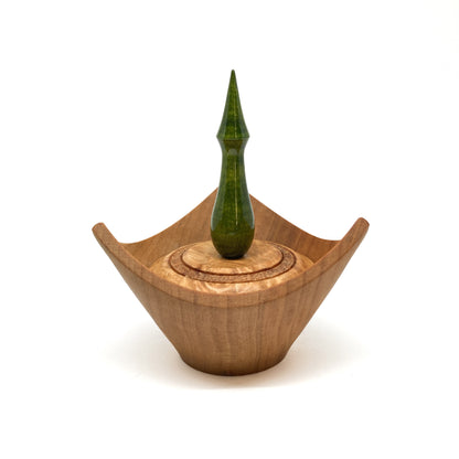 A turned wooden box with a pointed green finial on the lid.