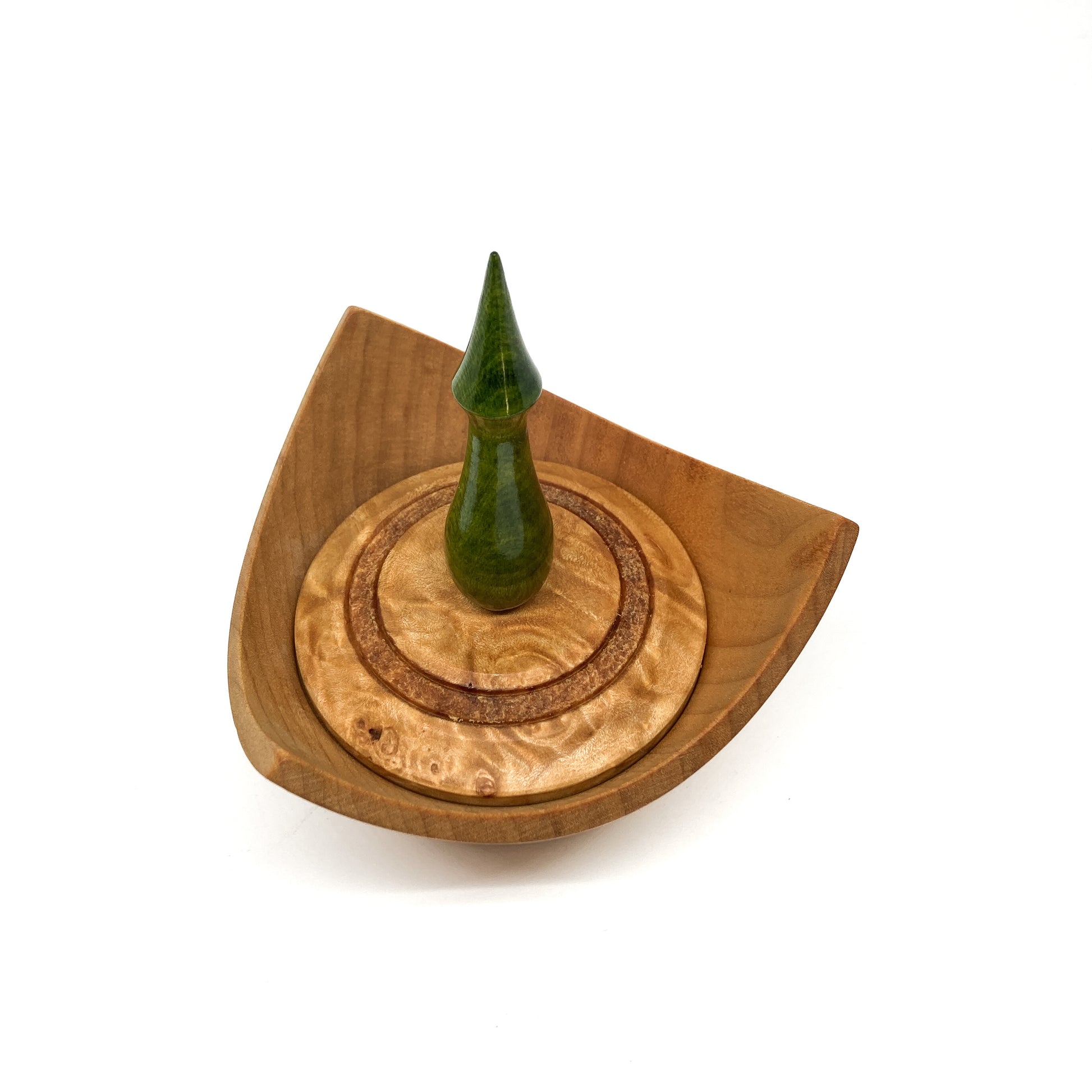 A turned wooden box with a pointed green finial on the lid, viewed from above.