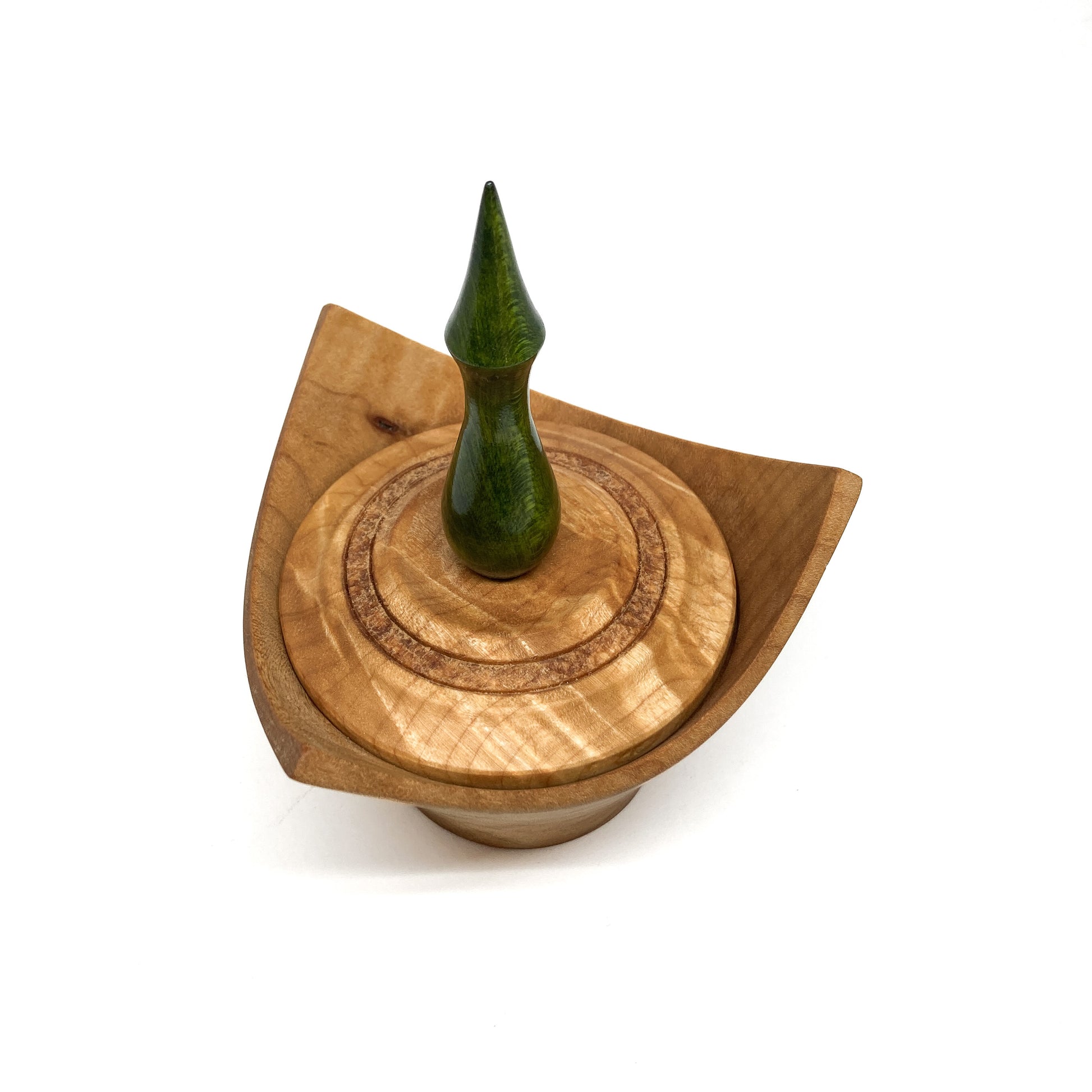 A turned wooden box with a pointed green finial on the lid, viewed from above.
