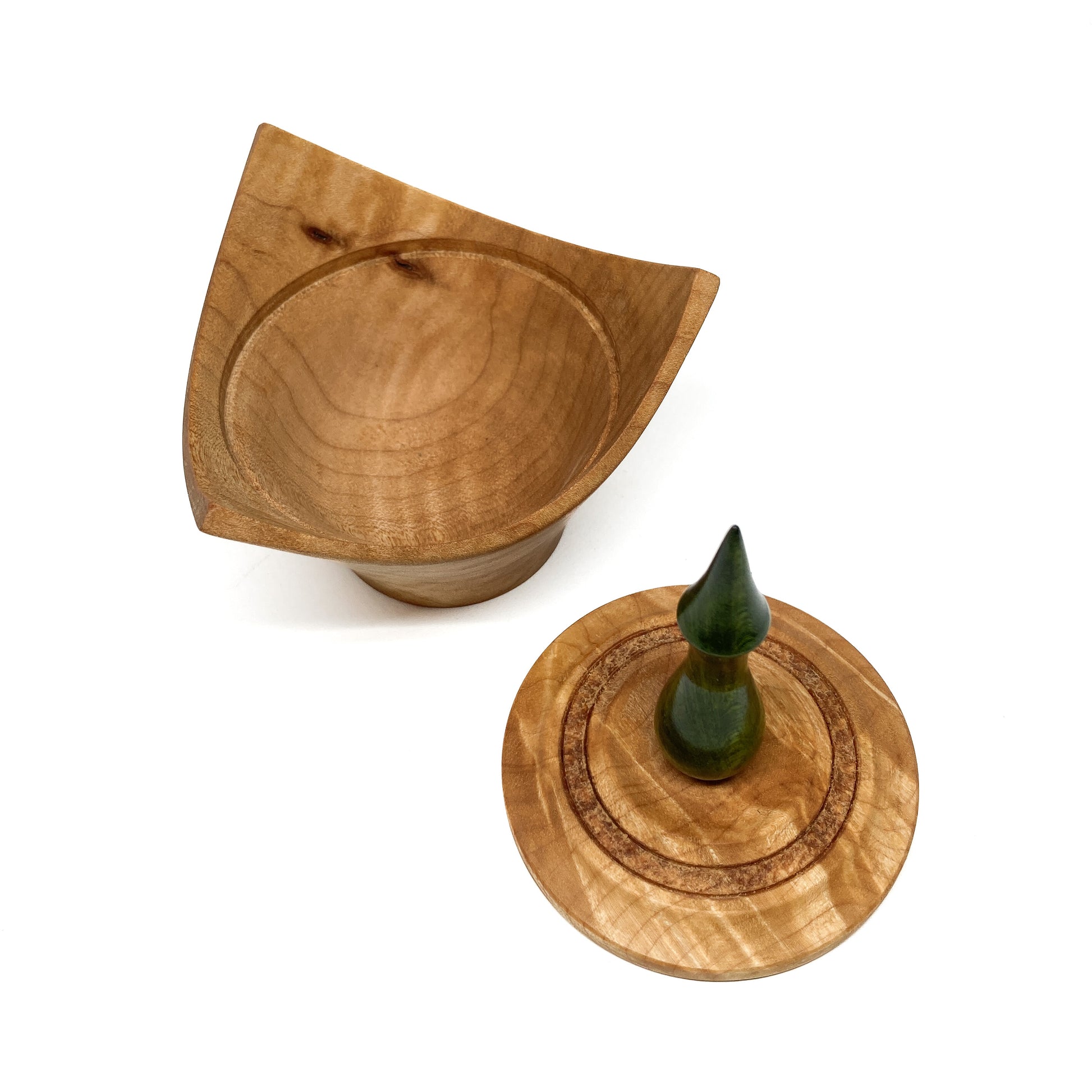 A turned wooden box with a pointed green finial on the lid, with the lid removed.