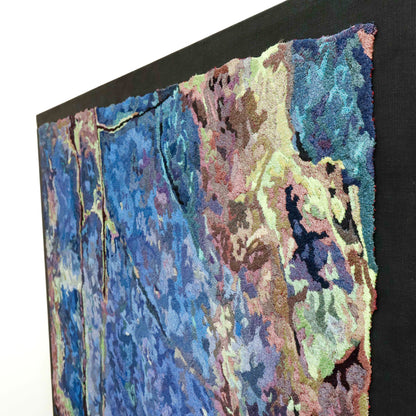 Angled view of a framed thread painting, showcasing dense stitching and colorful thread in a textured embroidery.