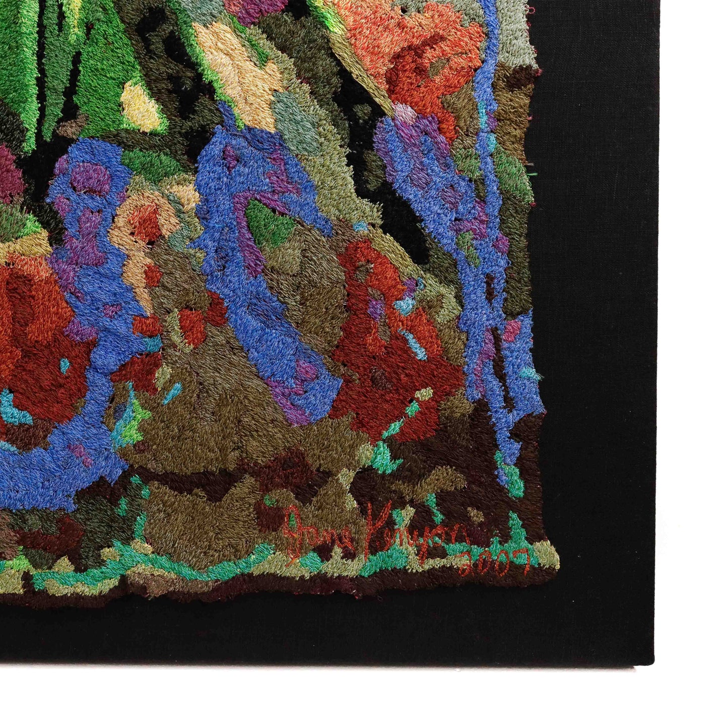 Framed thread tapestry close-up, showcasing dense, colorful thread stitching in an abstract embroidery design. Artist signature visible.