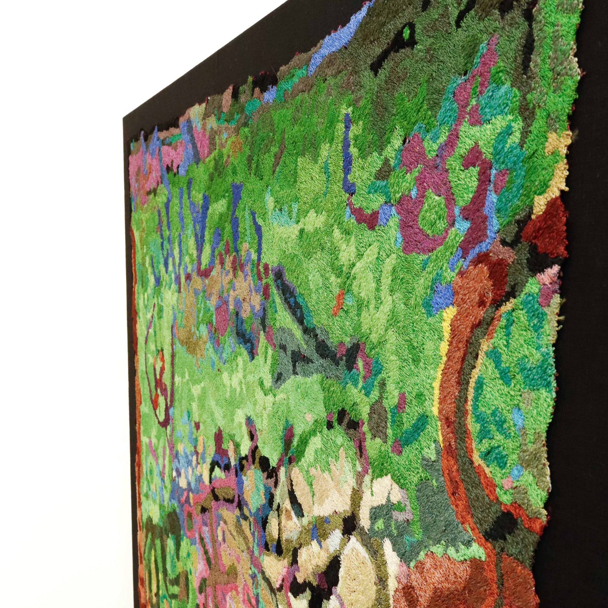 Angled view of a framed thread painting, showcasing dense, colorful thread stitching in an abstract embroidery design.