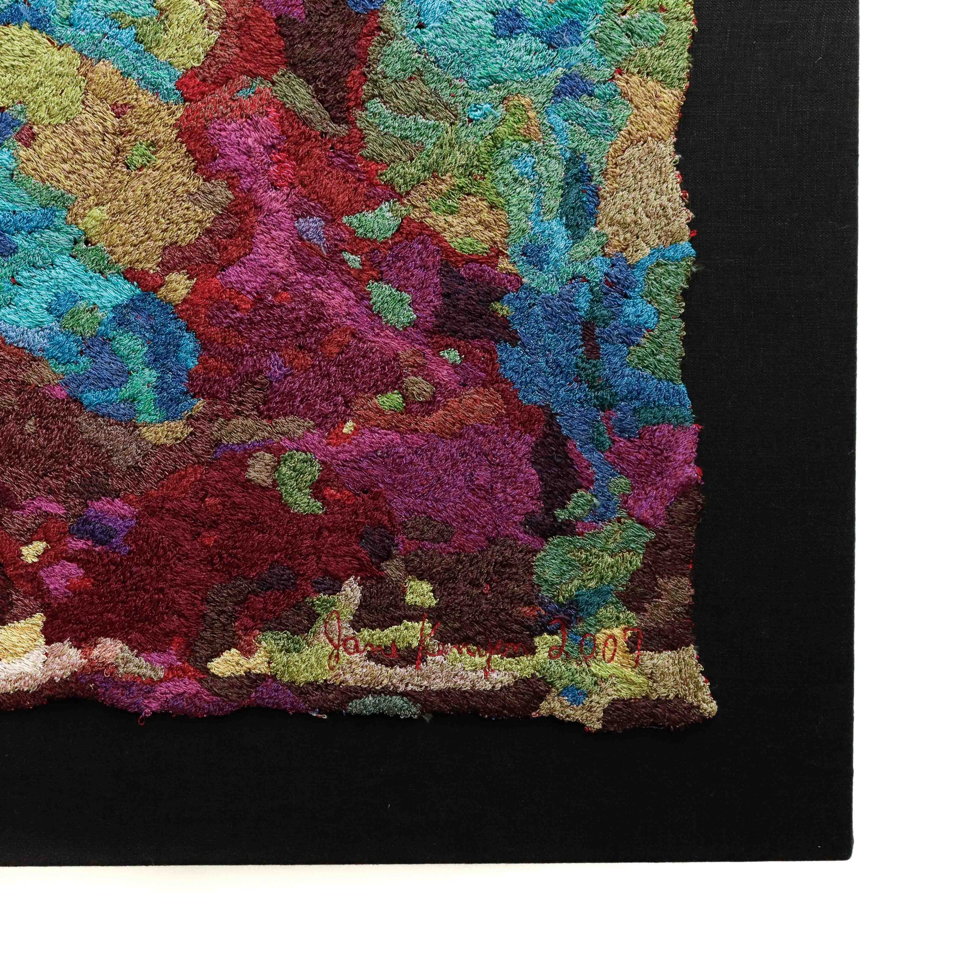Framed thread painting close-up, showcasing dense, colorful thread stitching in an abstract embroidery design. Artist signature visible.