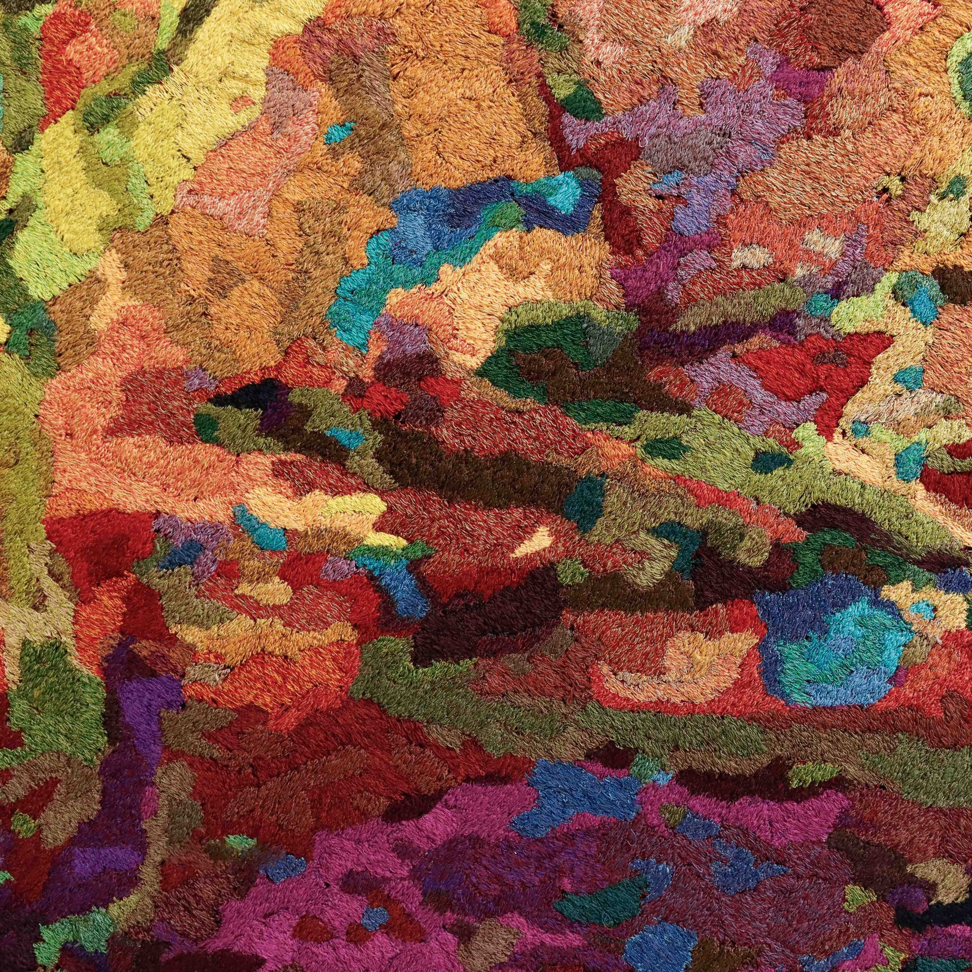 Detailed thread painting close-up, showcasing dense stitching and a vibrant array of colorful thread in a textured, abstract embroidery.