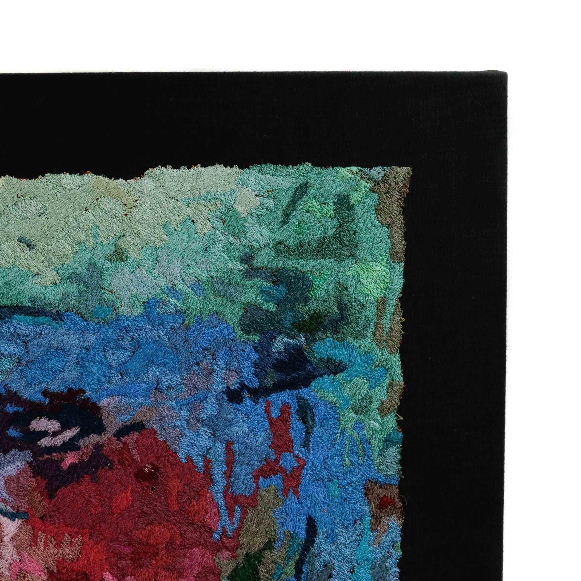Framed thread painting close-up, showcasing intricate stitching and colorful thread in an abstract embroidery design.