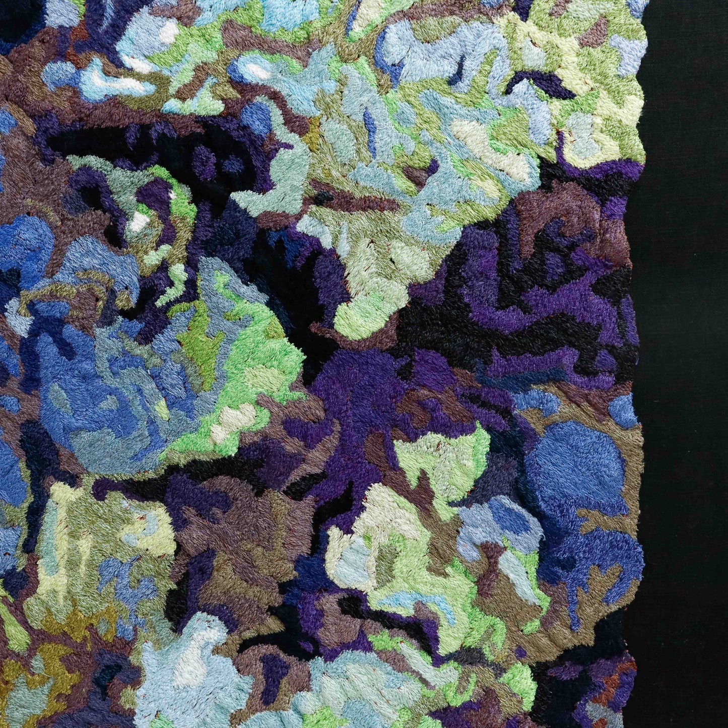A close-up of a thread painting, highlighting detailed stitching and colorful thread in an abstract thread painting.