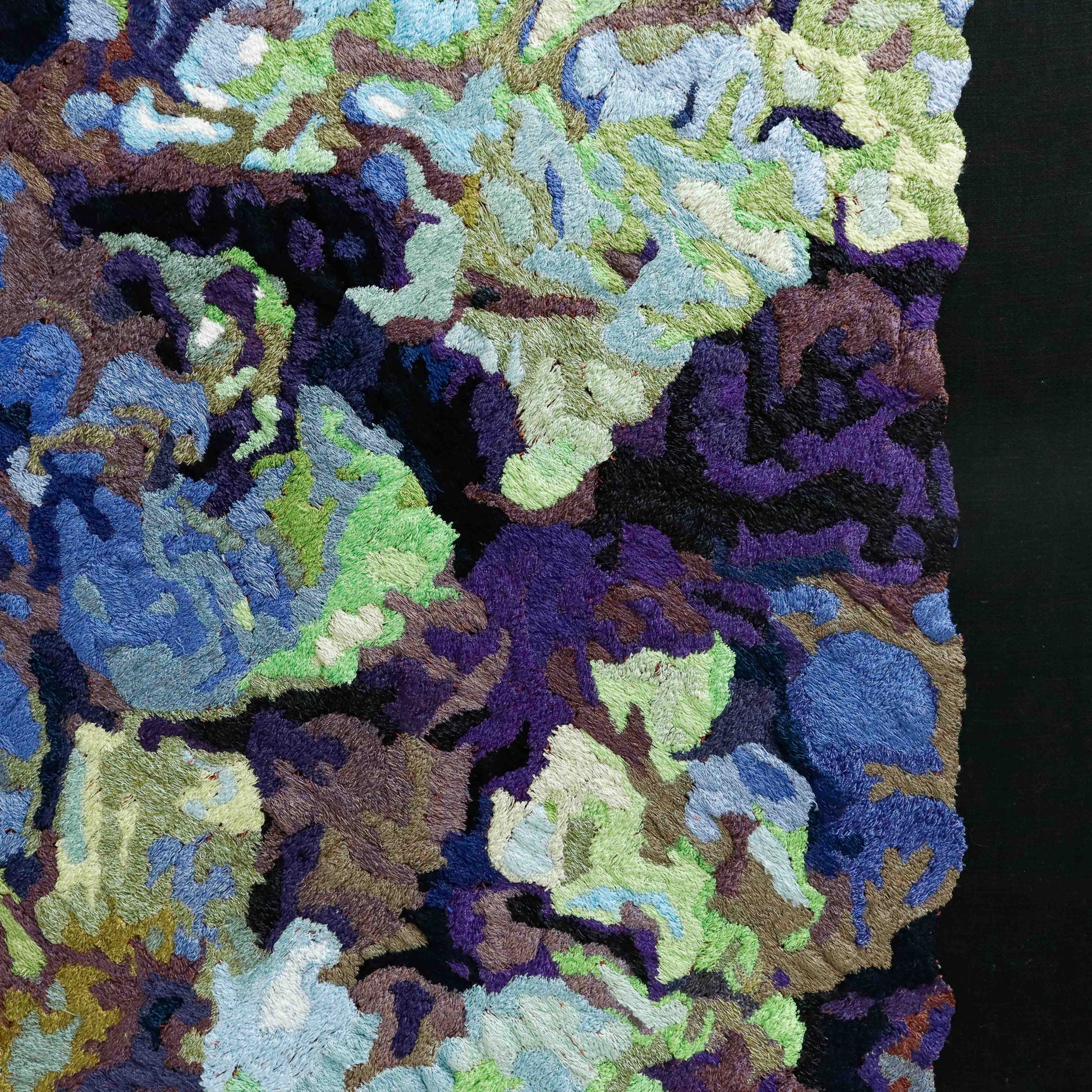 A close-up of a thread painting, highlighting detailed stitching and colorful thread in an abstract thread painting.