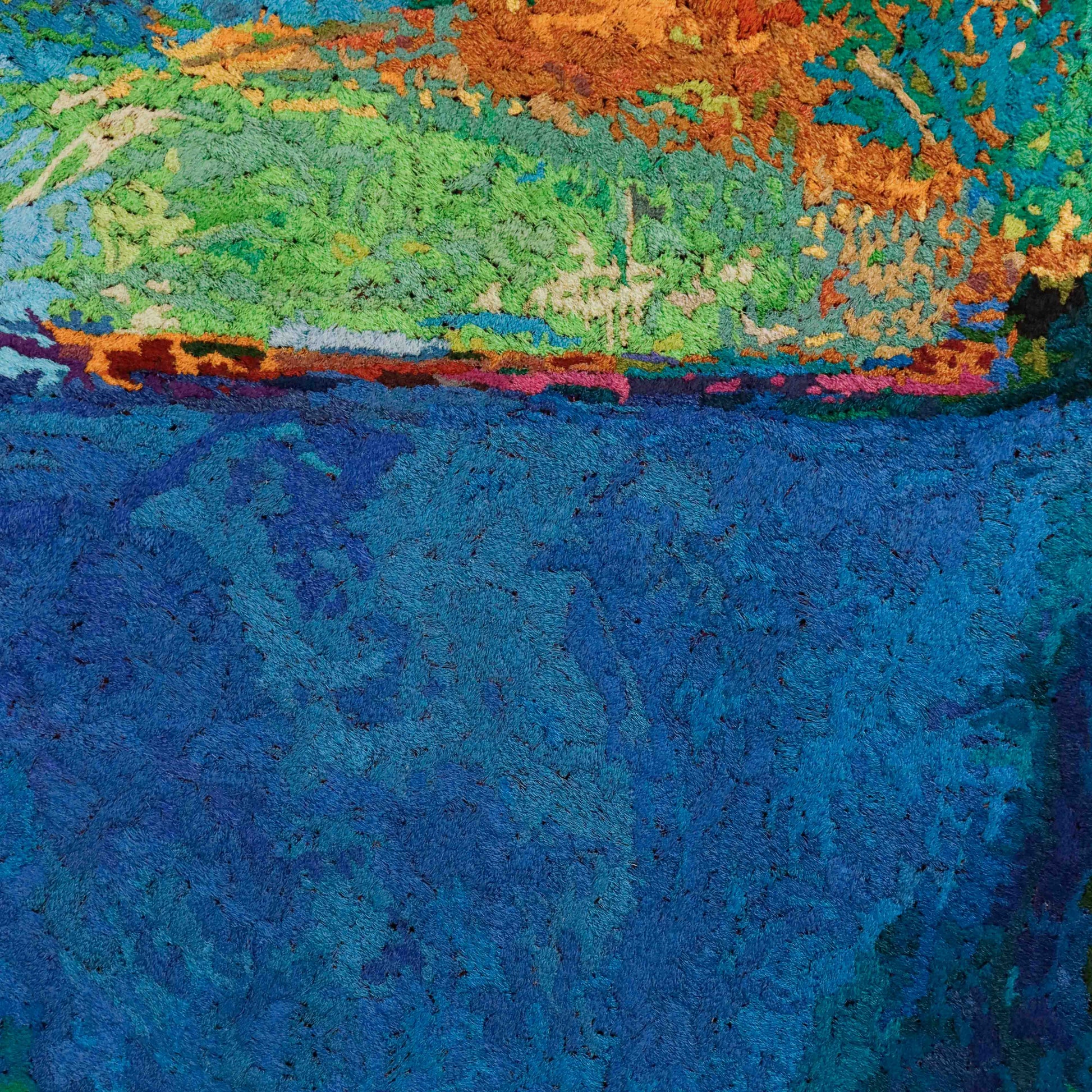A close-up of a thread painting with a landscape design, showcasing intricate stitching and colorful thread. 
