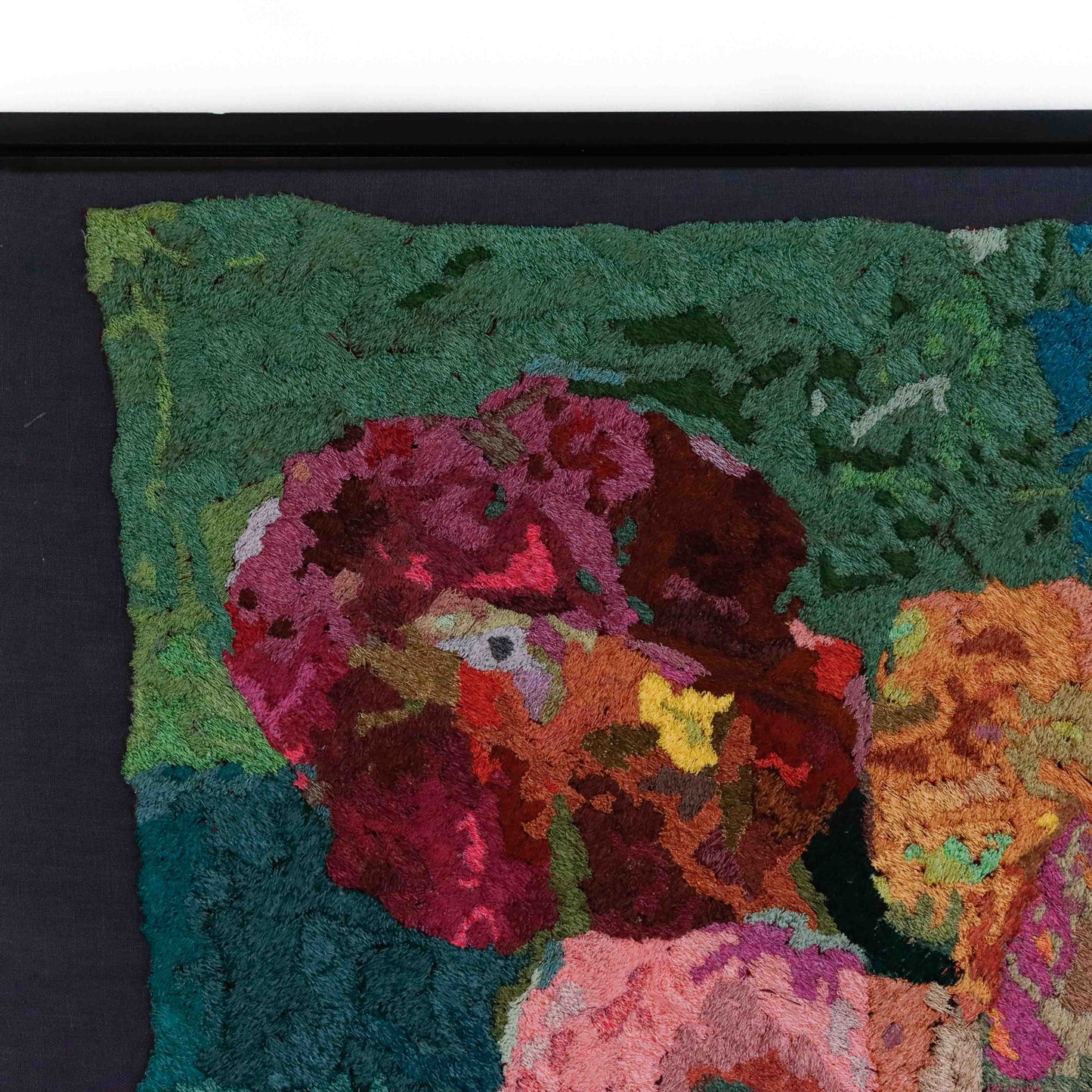A close-up of a thread painting featuring flowers, showcasing intricate stitching and colorful thread. 
