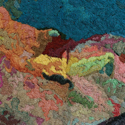 A close-up of a thread painting with a textured, abstract design, showcasing intricate stitching and colorful thread. 