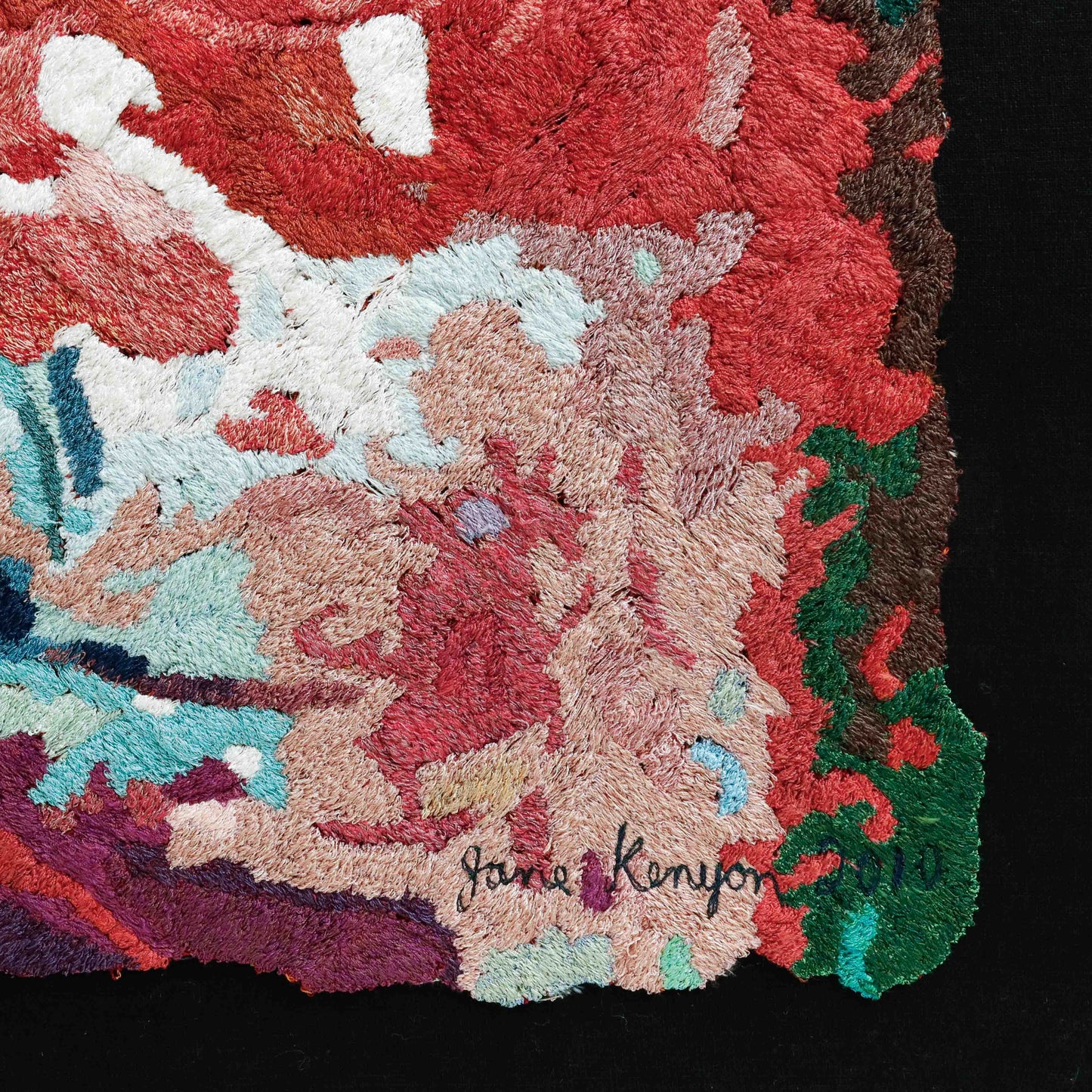 A close-up of a thread tapestry with a signature, showcasing intricate stitching and colorful thread. A beautiful thread painting by Jane Kenyon.