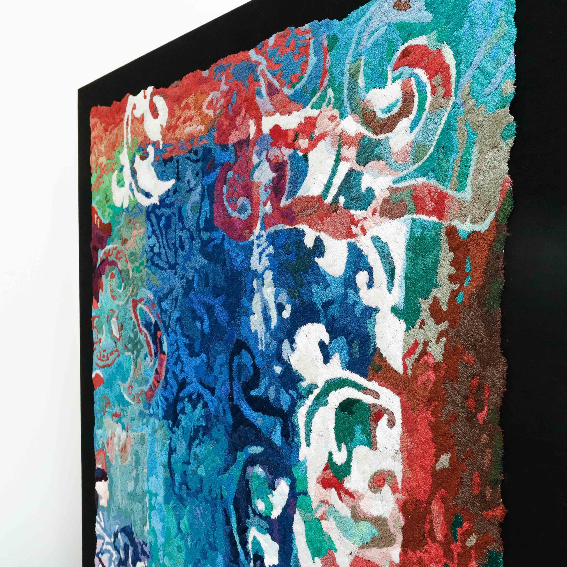 A framed thread tapestry, angled view, displaying intricate stitching and colorful thread in a pattern-rich thread painting.