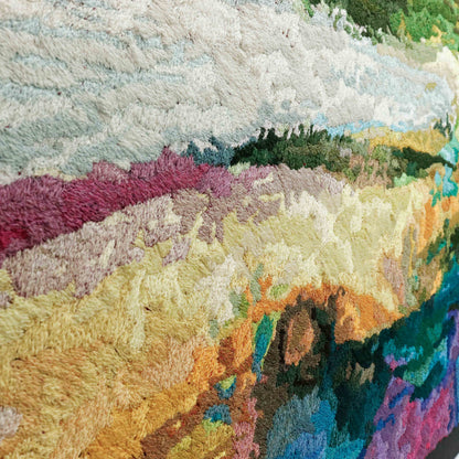 A close-up of a thread tapestry with a landscape design, showcasing intricate stitching and colorful thread. 