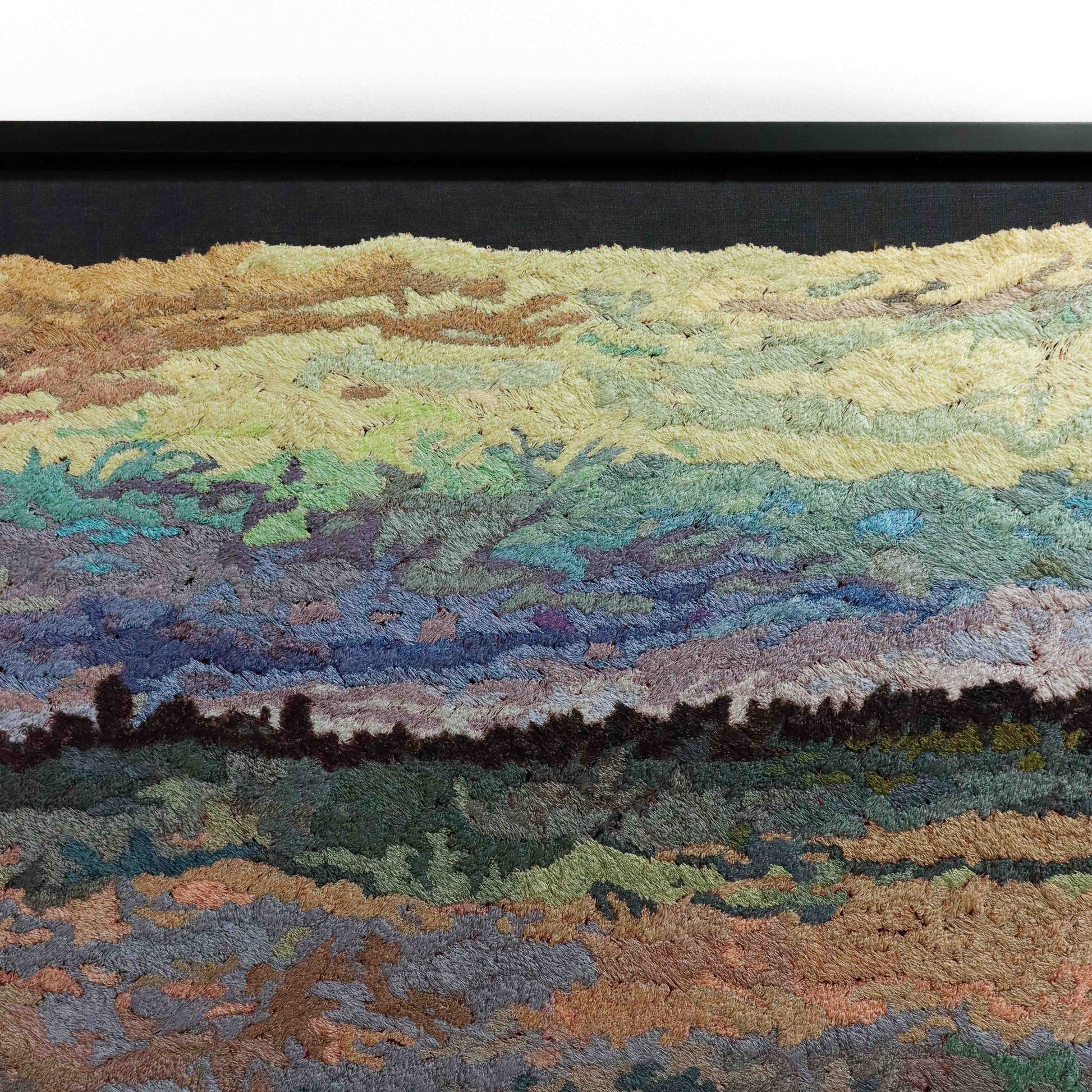 A close-up of a thread tapestry with a landscape design, showcasing intricate stitching and colorful thread.