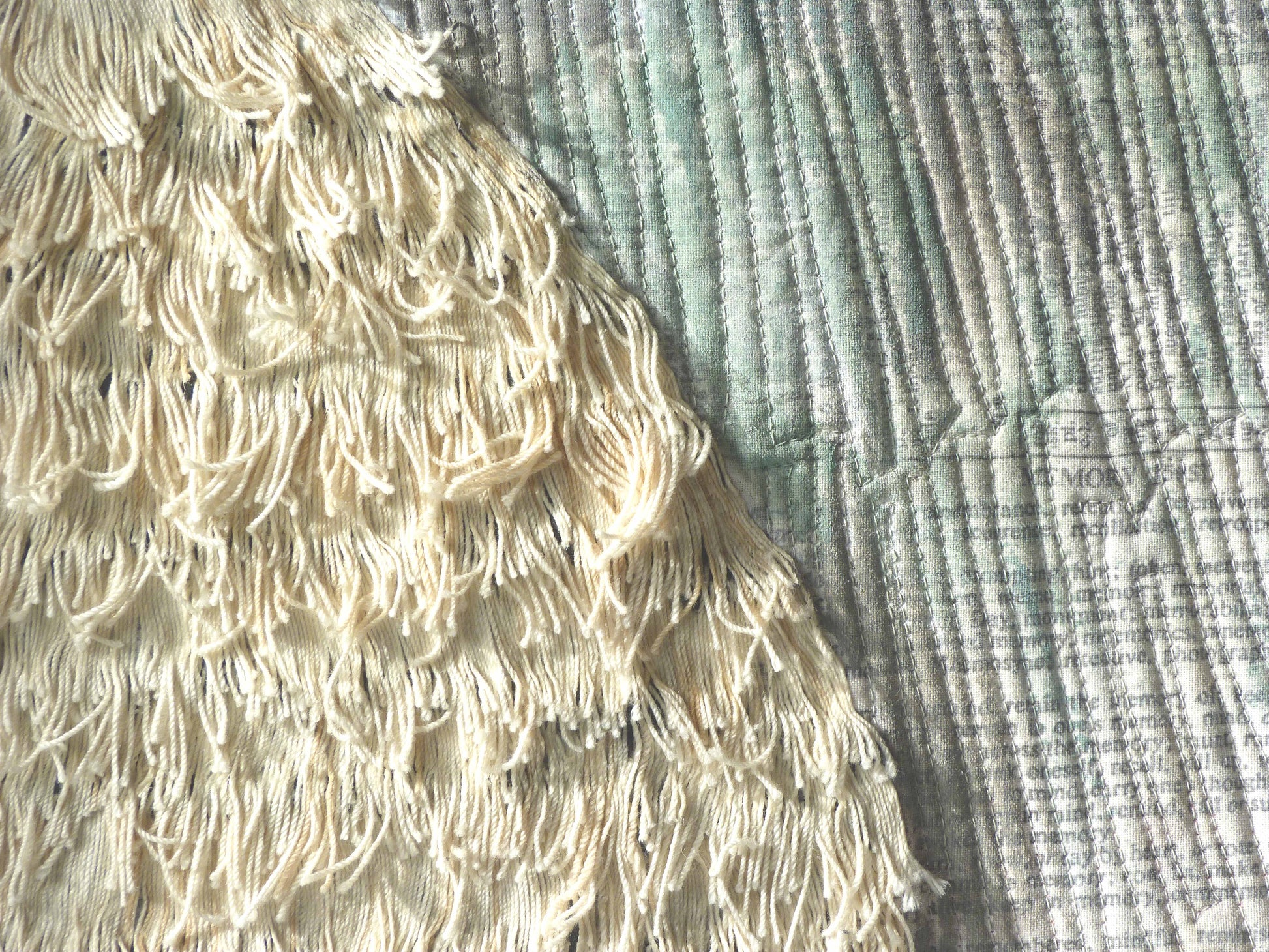 Close-up of textured textile art: layered fringe detail on a printed fabric surface.
