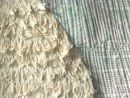 Close-up of textured textile art: layered fringe detail on a printed fabric surface.