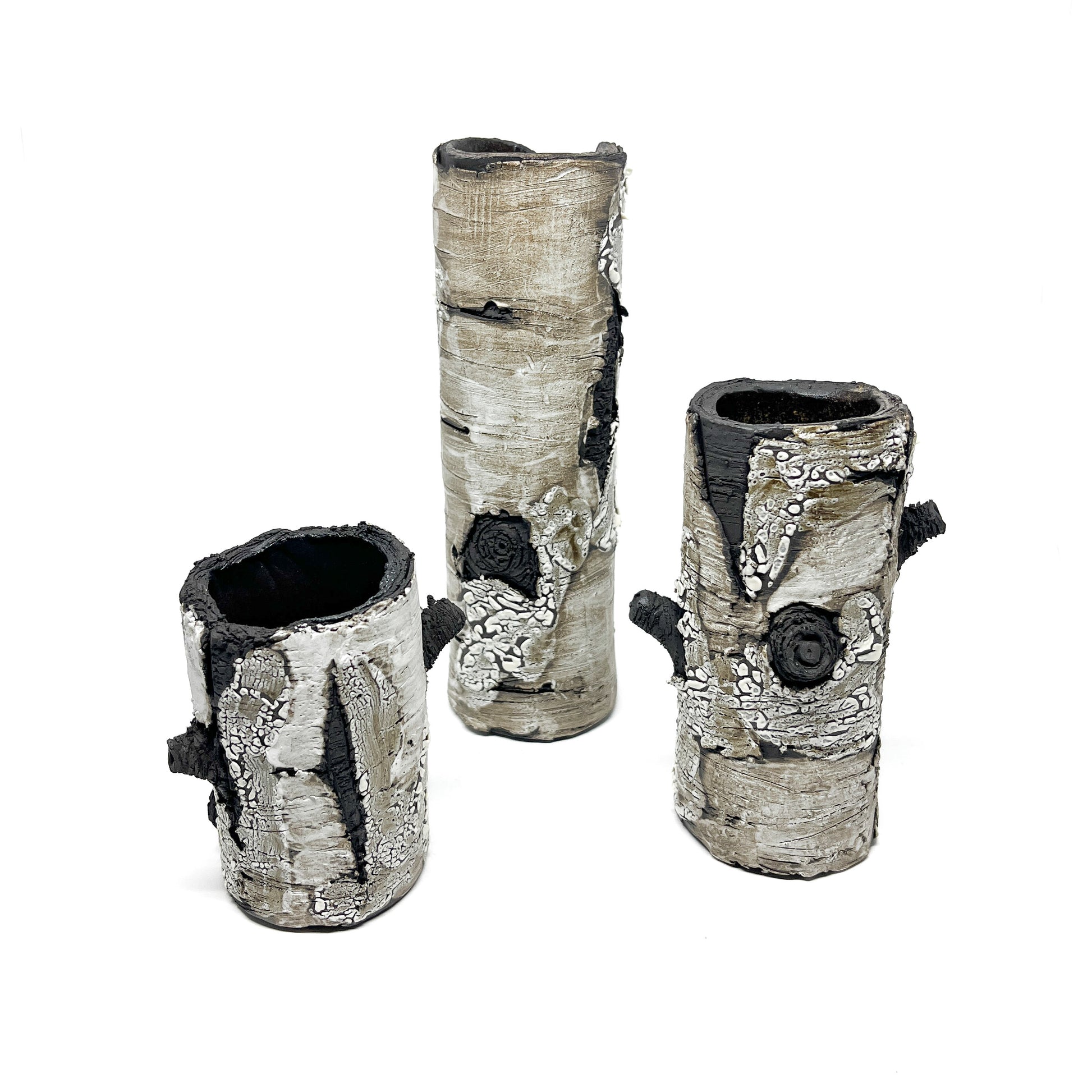 Three cylindrical vases resembling birch tree bark, with black and white textured surfaces.