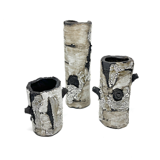 Three cylindrical vases resembling birch tree bark, with black and white textured surfaces.