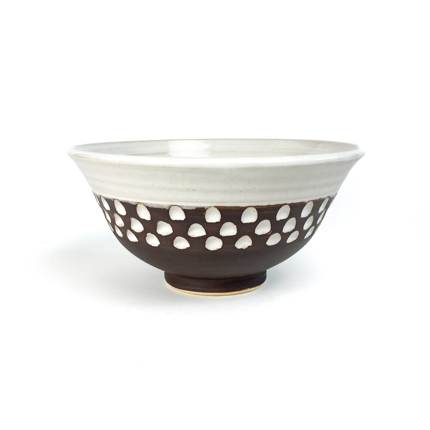 A two-toned bowl with a white rim and brown base featuring white carved details.