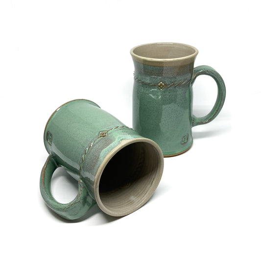 Two seafoam green glazed ceramic steins with rope designs and maker's marks, one upright and one tilted.