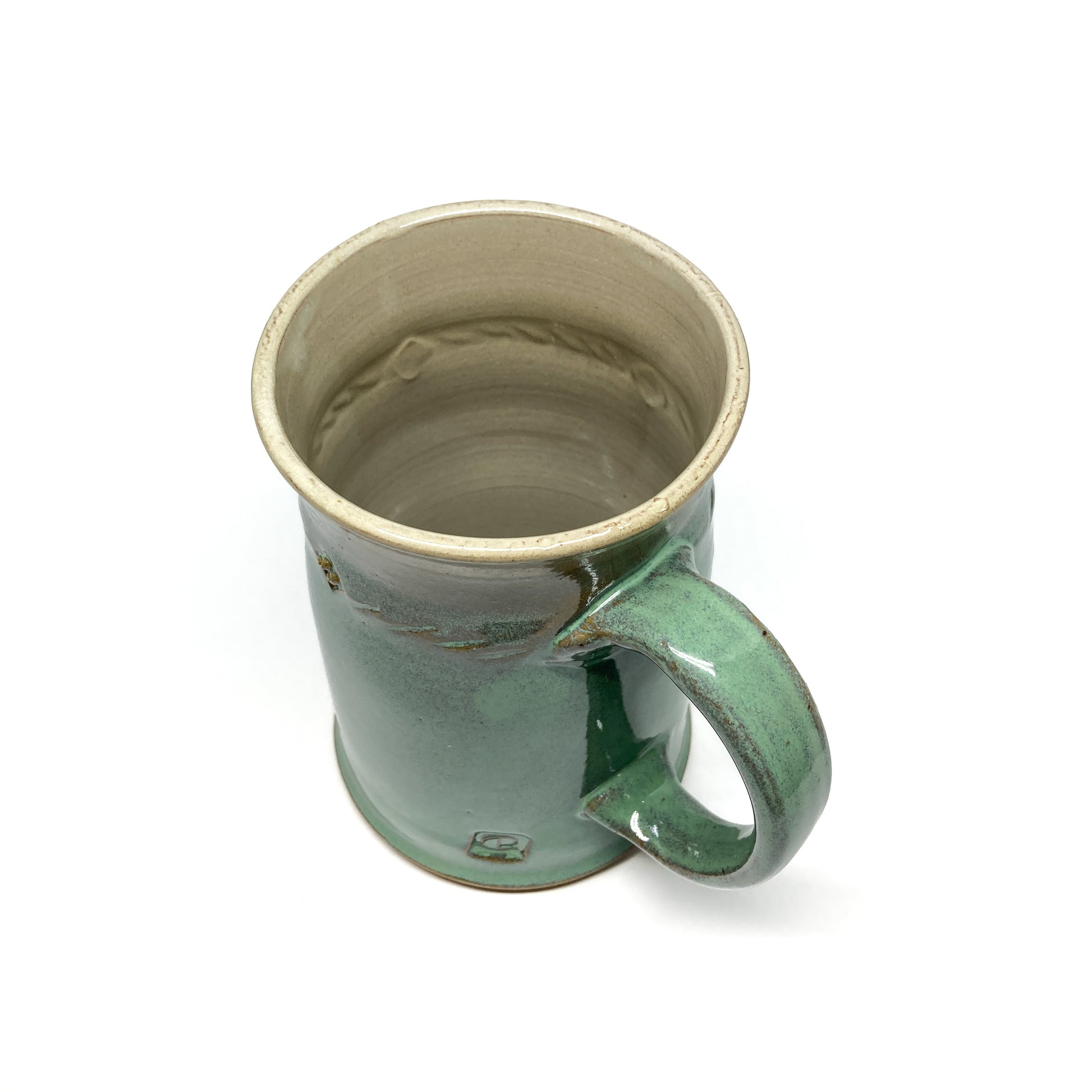 Overhead angled view of a seafoam green glazed ceramic stein with a rope design and a curved handle.
