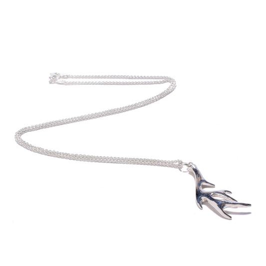 A delicate silver chain necklace features a pendant shaped like stylized deer antlers.
