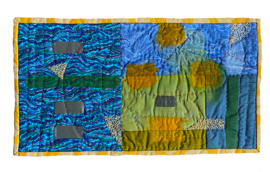 Abstract textile art featuring blocks of blue, green, and yellow fabrics with varied patterns and stitching.