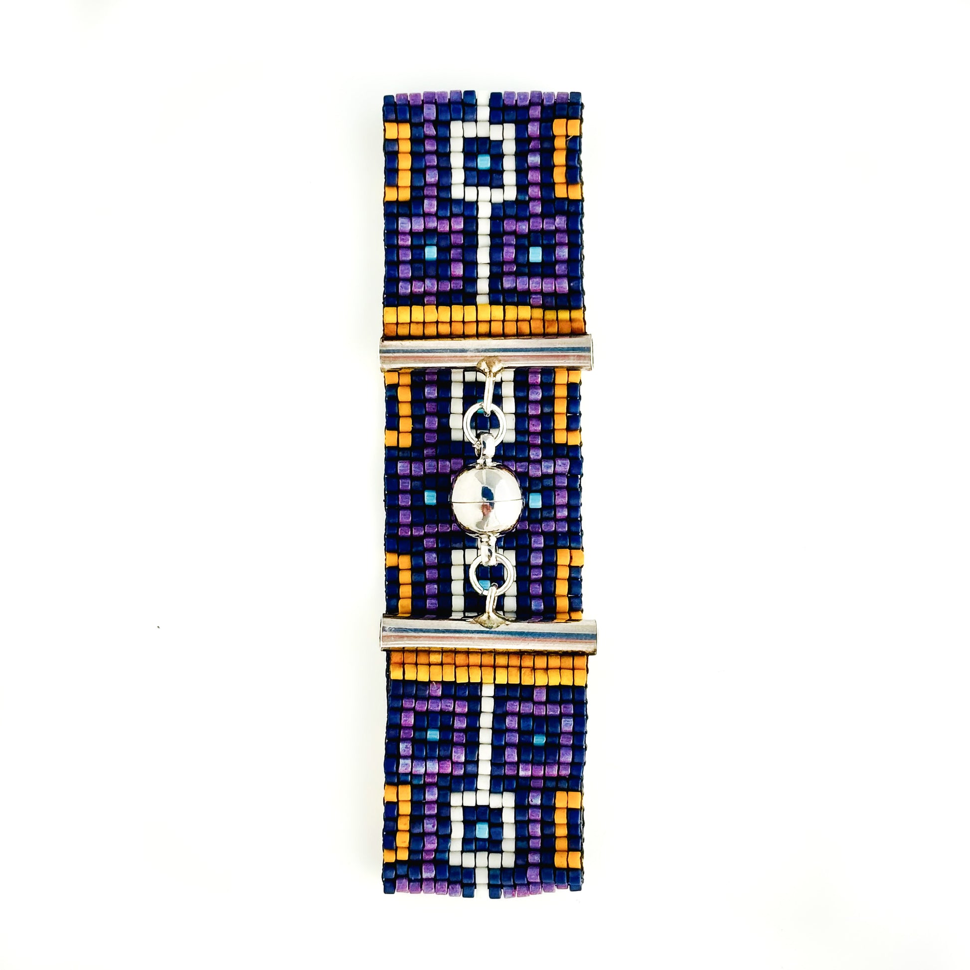 A flat lay shows a beaded bracelet with a geometric design in purple, blue, orange, and white and a silver magnetic clasp.