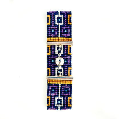 A flat lay shows a beaded bracelet with a geometric design in purple, blue, orange, and white and a silver magnetic clasp.