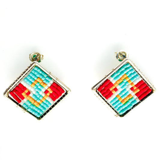 Two square stud earrings feature a vibrant geometric beadwork pattern in red, orange, turquoise, and white within silver frames.