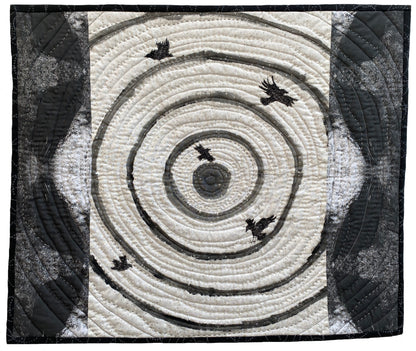 Textile art: concentric swirling lines with five dark birds scattered across the design.