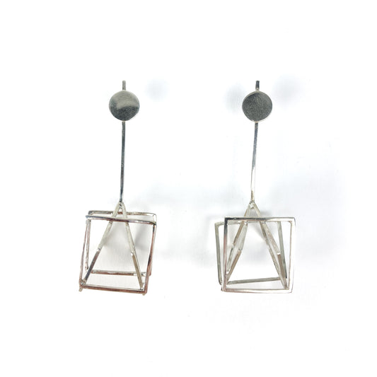 Two silver Cube-ism earrings with geometric cube and pyramid shapes.